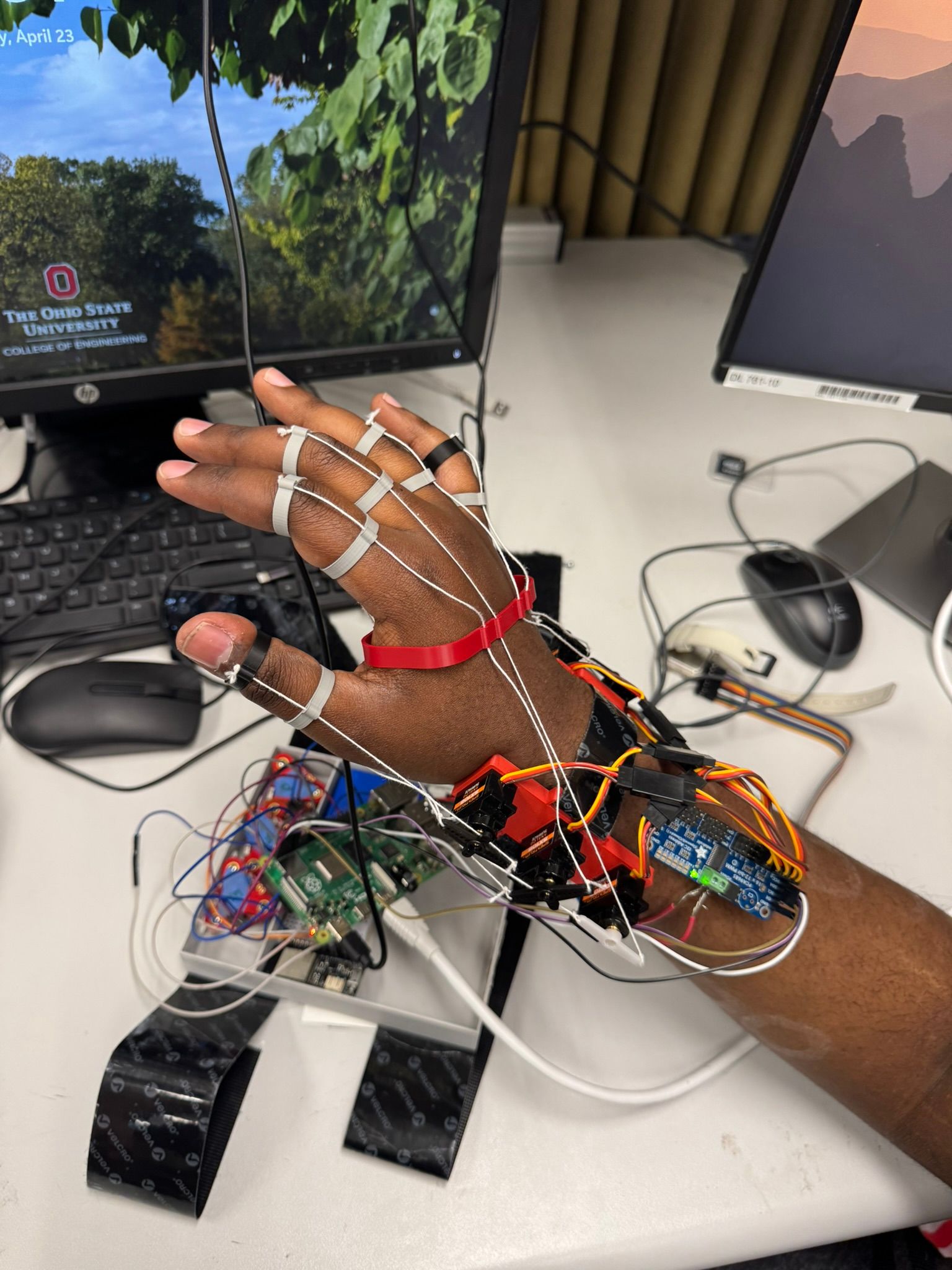 Close-up of the tendon-driven glove, with strings over each finger routed to servo motors mounted on the wrist.